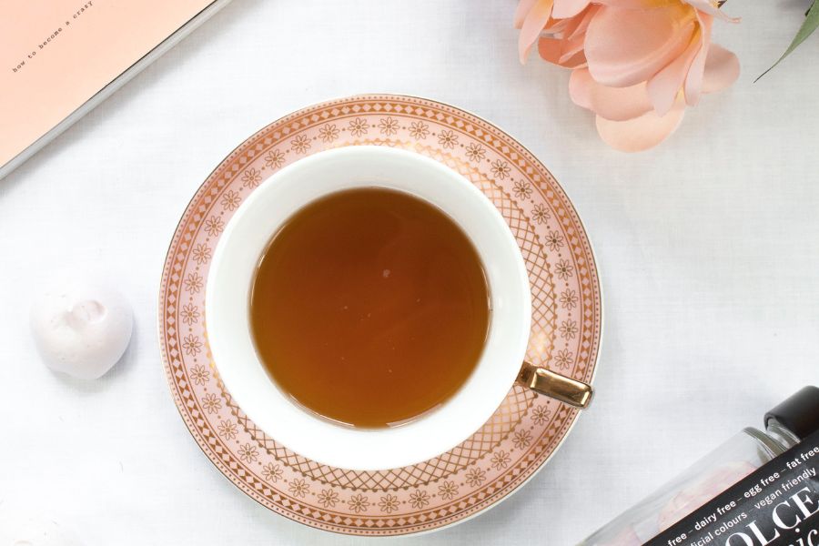 tea in a pink saucer as one of the drinks to reduce bloating 