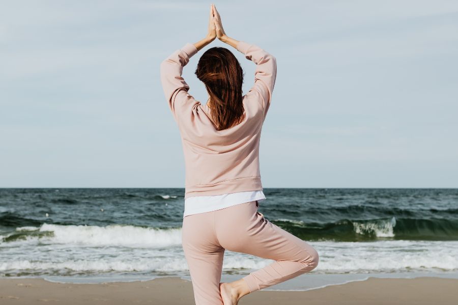 girl in yoga pose at seashore, setting healthy new year's resolutions