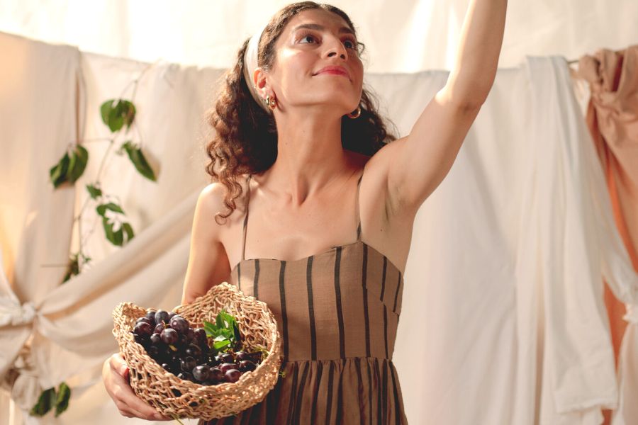woman in brown summer dress, carrying a basket of grapes, with a positive mindset for healthy living 