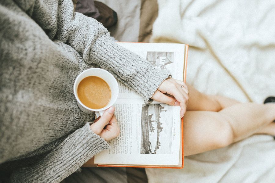woman reading book with coffee for winter self-care ideas