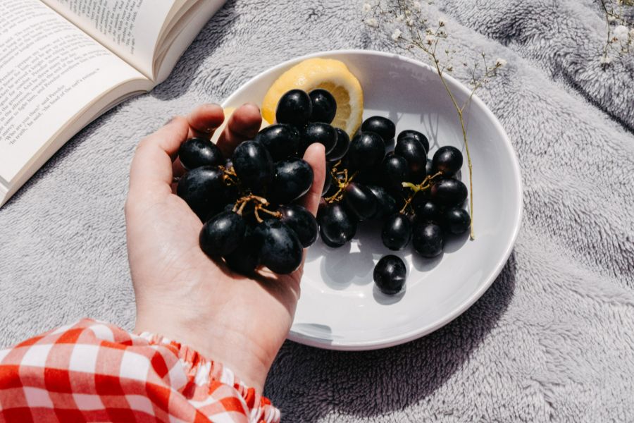 woman's hand in a plate of grapes as she practices ways to stop overeating