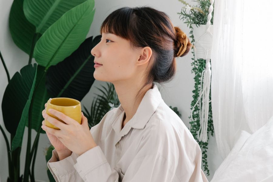 girl sitting in bed with mug getting ready to practice healthy morning routine ideas