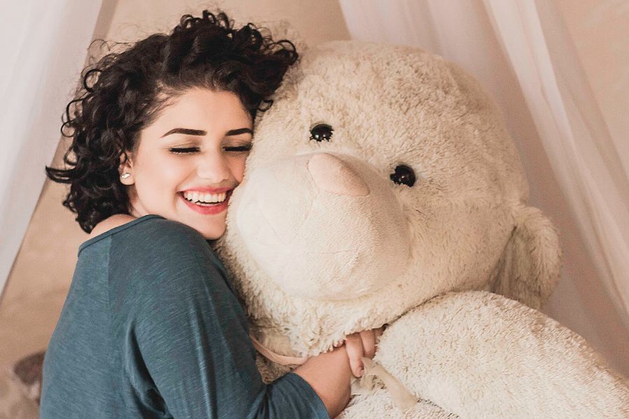 girl hugging a giant teddy bear practicing affirmations for self-love and healing 