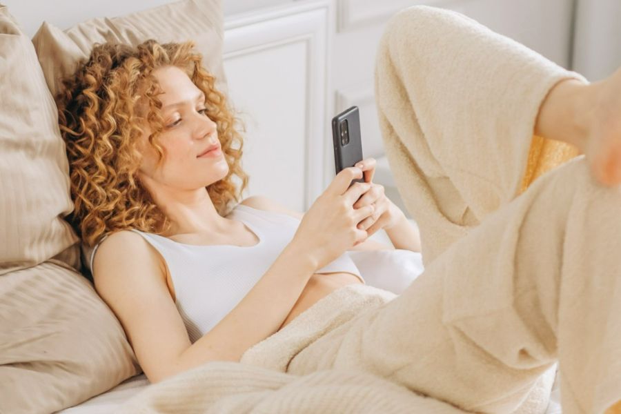 woman lying on pillow reading on phone about what to do when you don't feel like doing anything