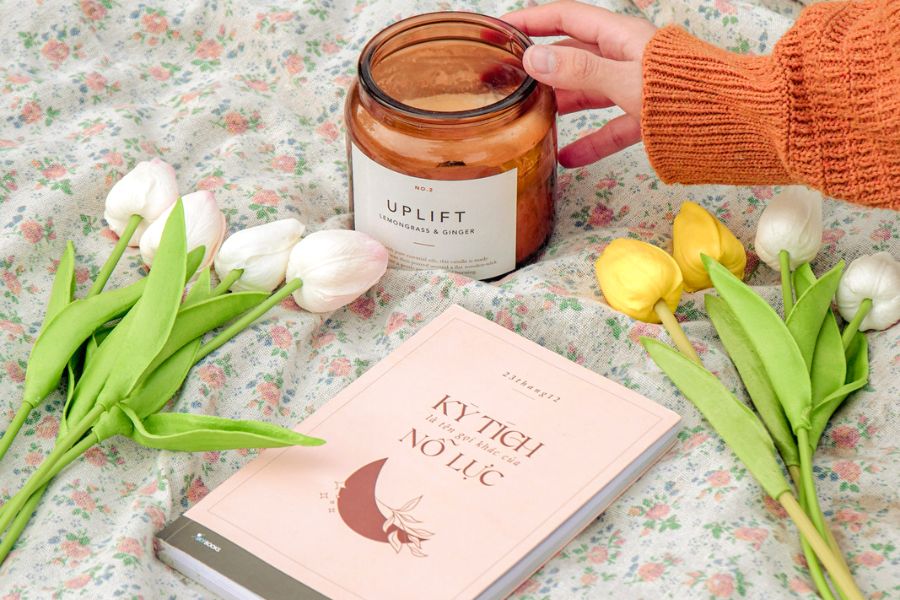rose buds, a pink cover book, and a woman's fingers touching a candle jar as she learns how to be kind to yourself