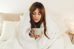 woman wrapped in a white blanket drinking tea to stop being sad