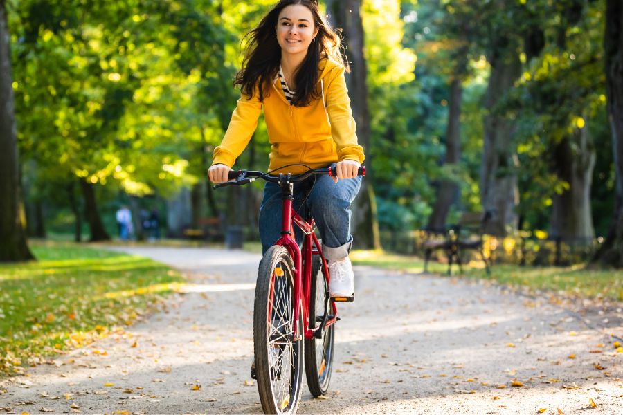 woman wearing yellow jacket riding a bike in autumn