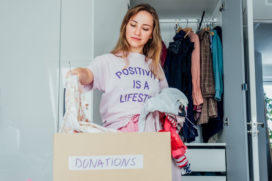 woman throwing clothes in donations box to make space for fall clothing