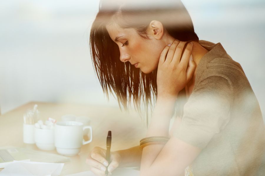 woman writing with pen with coffee on table