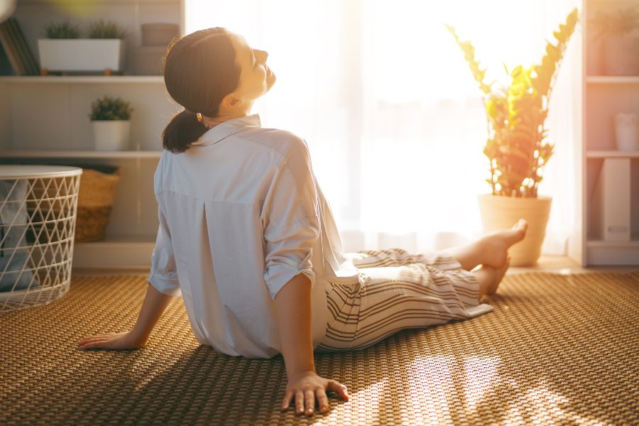 woman relaxing on floor while sunlight comes in through curtains 