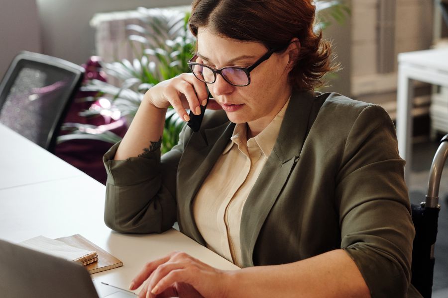 woman on phone while typing on laptop