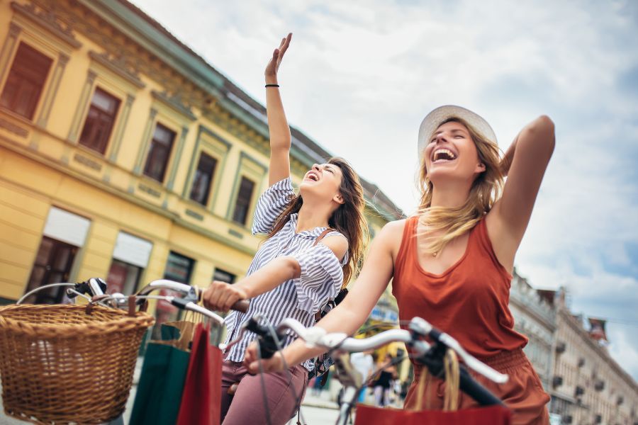 two women riding bicycles shouting in happiness with eyes closed