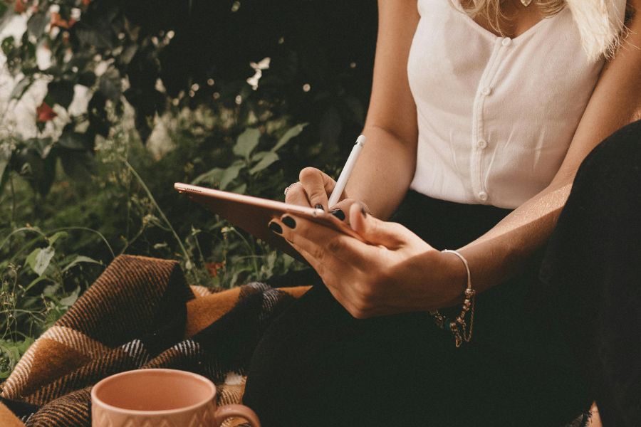 writing in tablet in nature with coffee