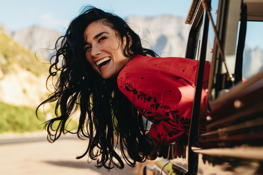 woman laughing with head out of car window