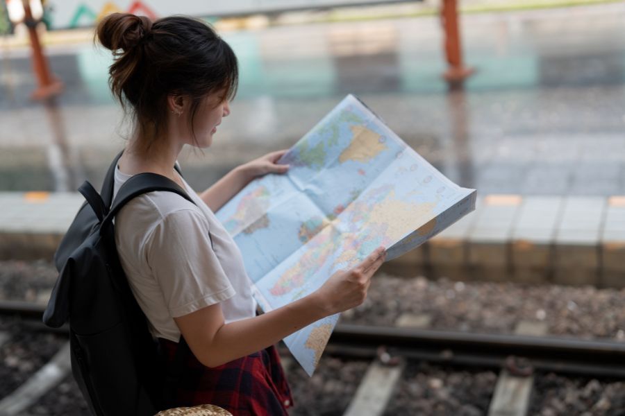 woman with backpack looking at world map
