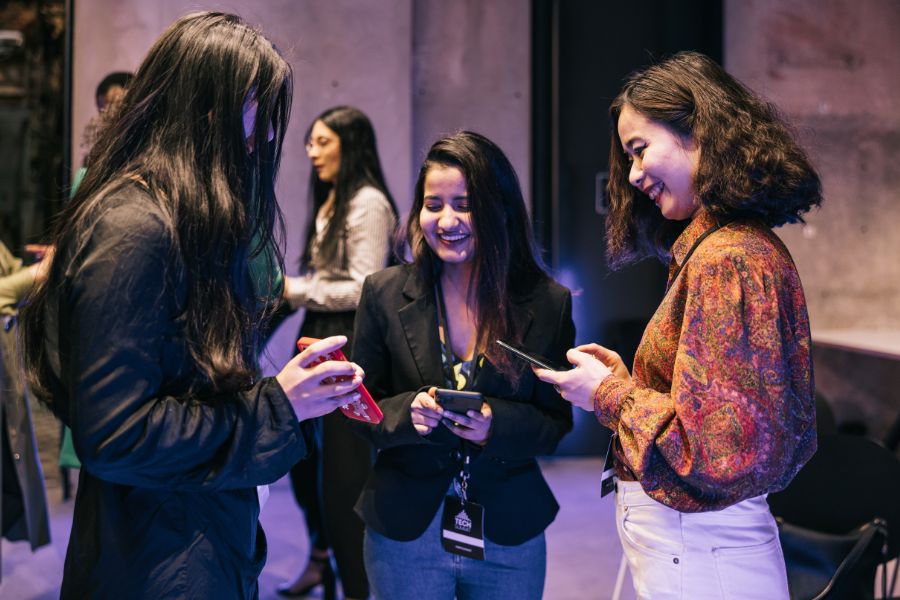 three women exchanging numbers while smiling and laughing