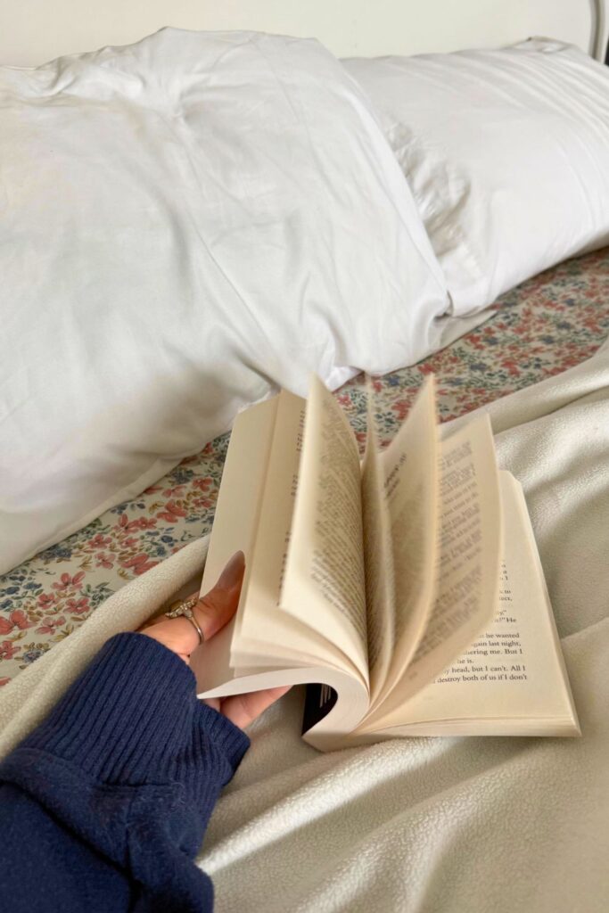 hand flipping pages of a book in bed