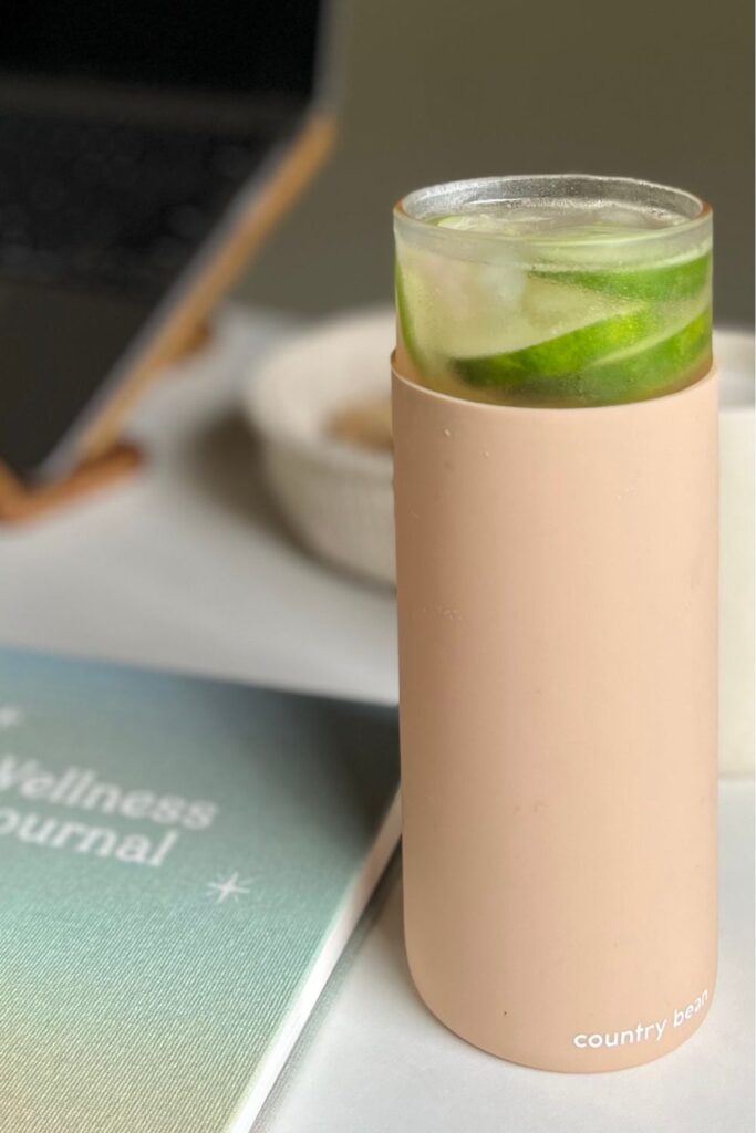 a peach color container of water with cucumber floating on top