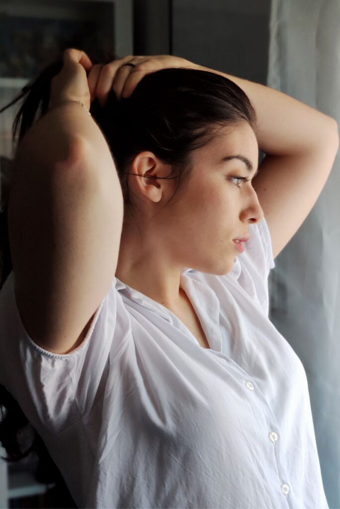 side view of woman tying her hair in a pony