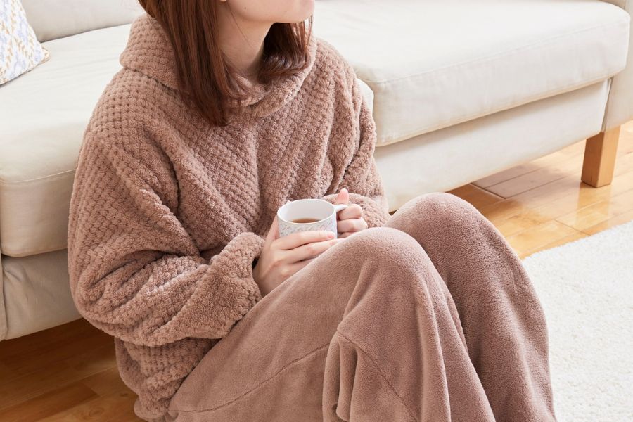 woman wearing peach winter clothes holding tea in hand