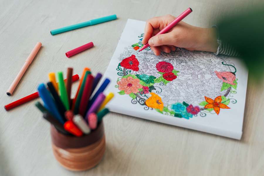 coloring in a coloring book with colors lying around on table