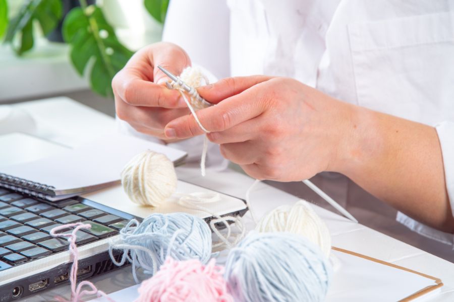 knitting in front of laptop on table