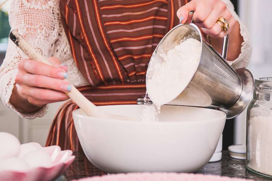 adding flour to a sugar bowl while baking