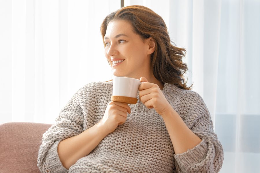 woman smiling while holding tea cup in hand