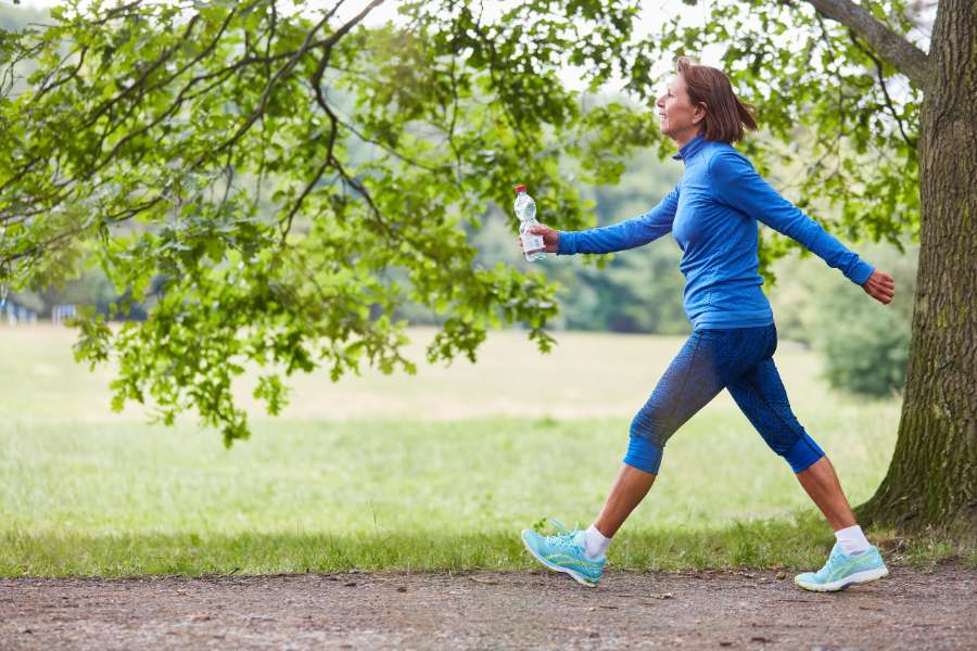 woman walking fast in a blue sweatshirt and knee-length leggings, aqua-blue shoes