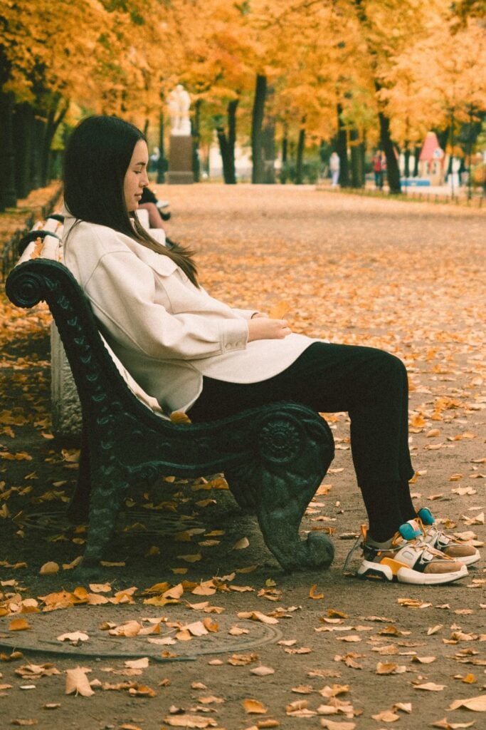 woman sitting on a park bench in autumn