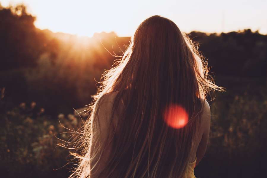 back view of woman watching sunset in a greenery