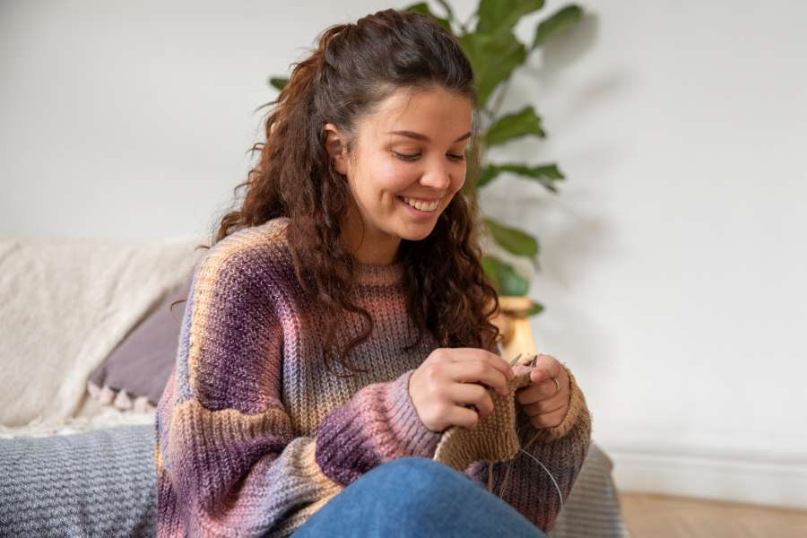 happy woman knitting, wearing a sweater