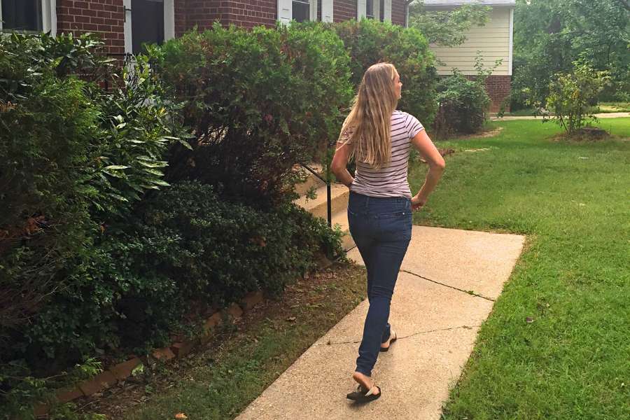 back view of a woman walking on path to her house