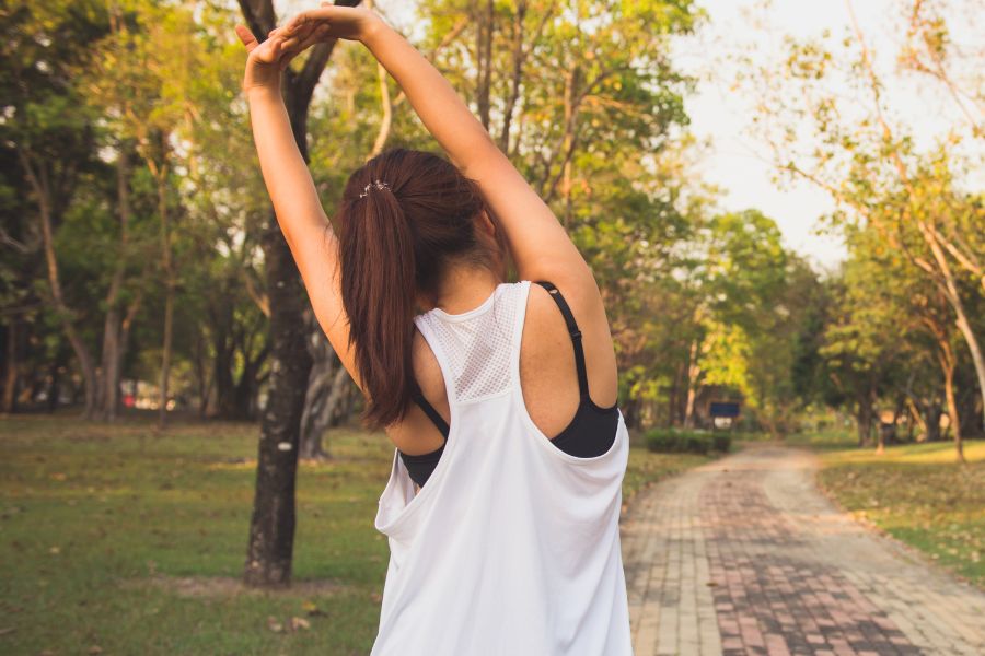 back shot of woman stretching in park