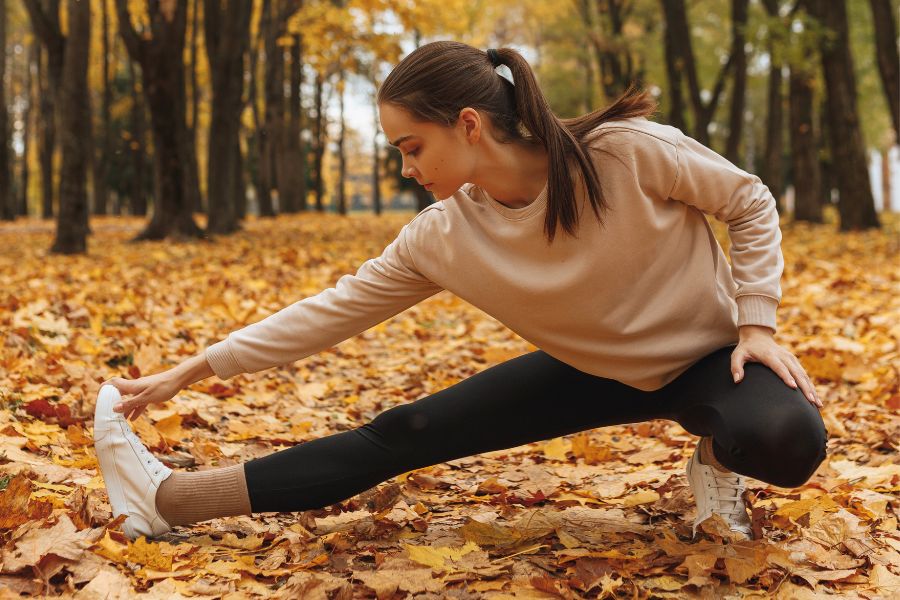 woman stretching in autumn leaves